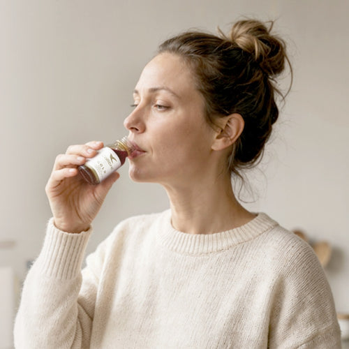 Woman drinking a Collibre Gold collagen shot in the morning