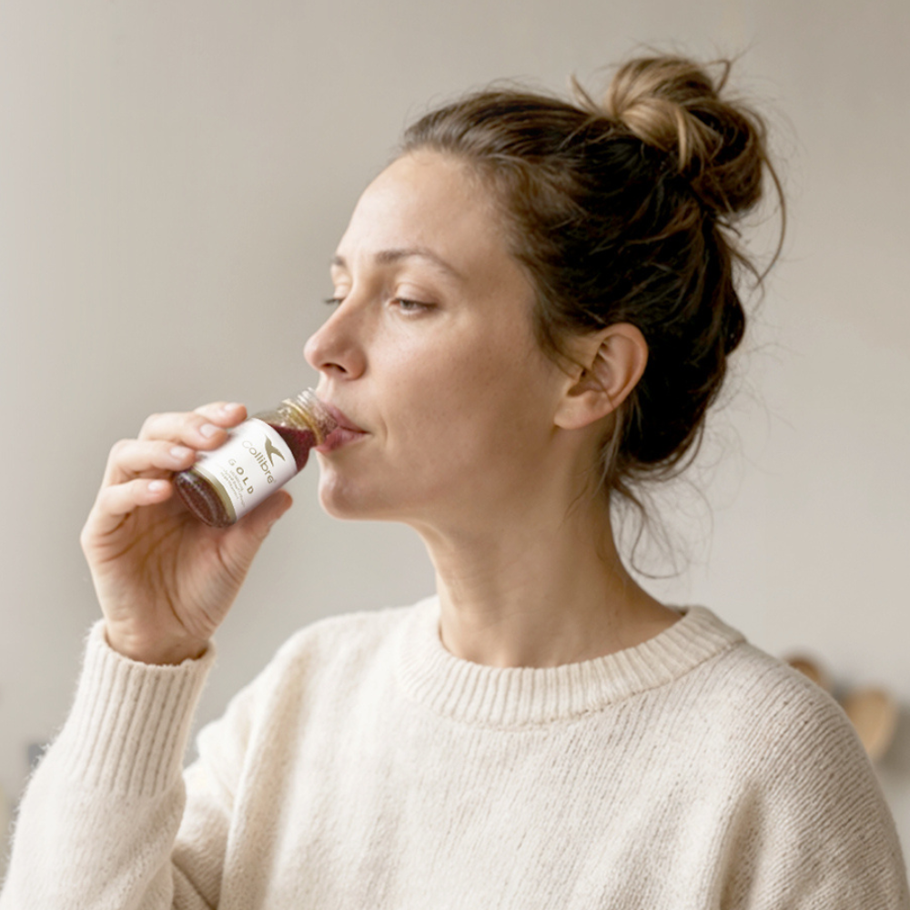 Woman drinking a Collibre Gold collagen shot in the morning