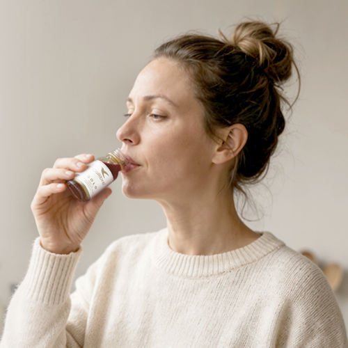 Woman drinking a Collibre Gold collagen shot in the morning